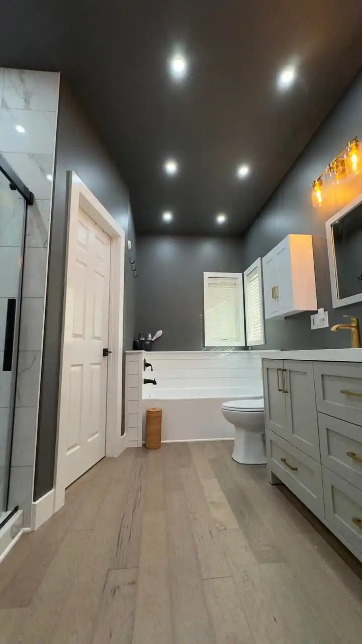 Hey there, check out this cool Conroe bathroom remodeling! Bright recessed lights, a sleek tub, and a stylish vanity with gold faucets create a warm vibe. Wood floors add charm—perfect for a modern upgrade!