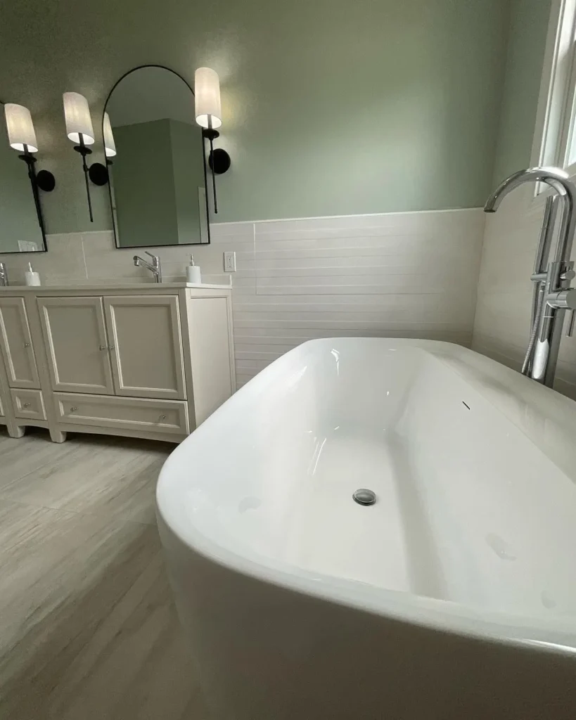 Modern bathroom with New Bathtub Fitting & Placement, featuring a sleek white freestanding tub, double vanity, and stylish lighting.